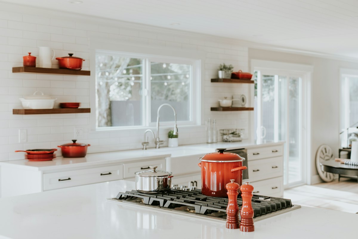 Bright kitchen with white quartz island, farmhouse sink, floating wooden open shelves, and subway tile.
